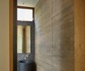 A concrete powder room wall plays off Stone Forest Veneto Sink and Mud Wood Chip Mosaic tile.