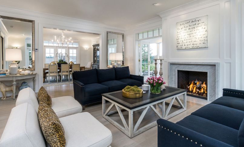 Navy blue sofas ground the light-filled formal living room that is walled by French doors.