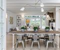 A rustic table is paired with modern brass lighting from Circa. The informal dining area is placed between the family room and kitchen and opens to the backyard pool.