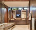 Designed to evoke a spa-like setting, the master bath boasts heated floors and tub deck, an extra-deep tub, and a hidden television set behind one of the vanity mirrors. The walls and tub surround are grey Fusano limestone, which has a lovely buttery texture. The cabinets are built from walnut.