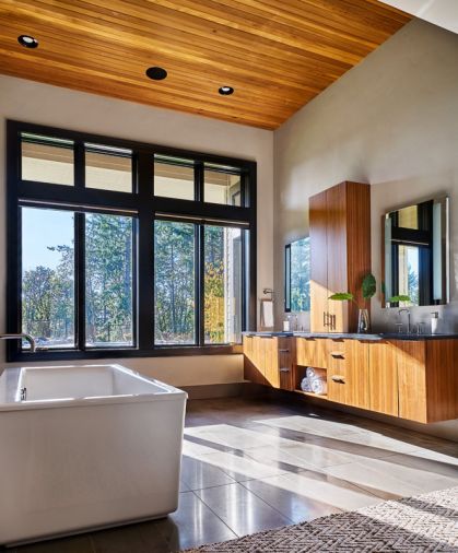 In order not to take up prime real estate in front of the master bath windows, GHID placed Heather’s soaking tub next to the entrance to Brandon’s “over-the-top” shower, featuring porcelain tile and mosaic stone floor, dual overhead rain shower heads and 4 wall shower units. Cedar ceilings provide warmth, countering the walnut cabinetry. 