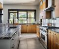 To bring more light into the kitchen, Collin used back painted slabs by Moonshadow as the backsplash for reflection and a calming antidote to the stainless appliances. Large porcelain Dal Tile flooring is found in kitchen, laundry and dining room.