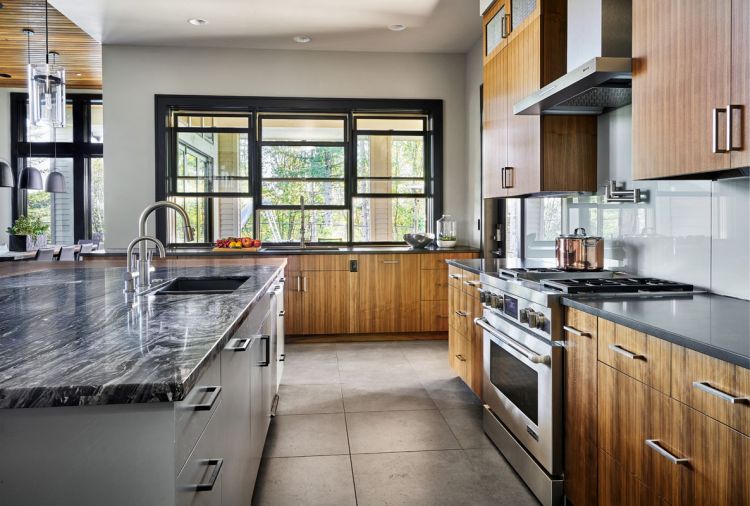 To bring more light into the kitchen, Collin used back painted slabs by Moonshadow as the backsplash for reflection and a calming antidote to the stainless appliances. Large porcelain Dal Tile flooring is found in kitchen, laundry and dining room.