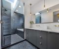 Pental black tiling, Kokeena slate doors and gold fixtures by Kohler create drama in the master bathroom.