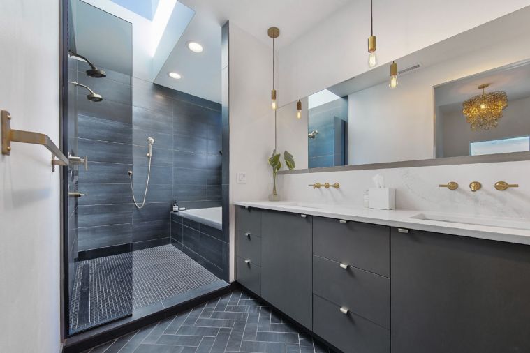 Pental black tiling, Kokeena slate doors and gold fixtures by Kohler create drama in the master bathroom.