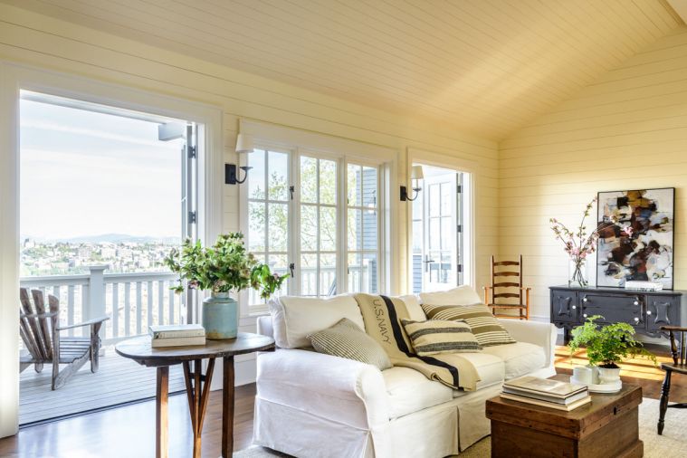 A small balcony off the living room makes it easy to enjoy the lake, mountain, and city views. Horizontal boards on the walls and ceiling give the home a clean, almost beach-y feeling.