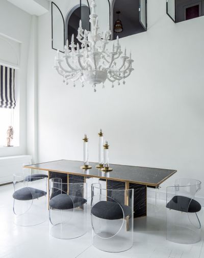 The Charles Hollis Jones Lucite chairs gather round the large dining table suitable for entertaining her many guests. Howe found the vintage brass candlesticks that tie to the table’s trim.striped barstool cushions continue the theme found in the Roman shades and Zebra head.