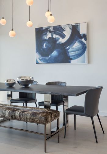 The dining room features a custom-made cowhide rug, colorful artwork  sourced through Vanillawood, with hand-blown glass pendants from SkLO of California.