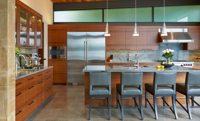 Natural materials like stone tile floors and horizontal-grain Afrormosia cabinetry give the kitchen texture and interest while maintaining an understated aesthetic. These homeowners love to cook, so the kitchen is equipped with two sinks, an extra-large refrigerator, and a professional-grade oven and range to make entertaining and meal preparation a pleasure.