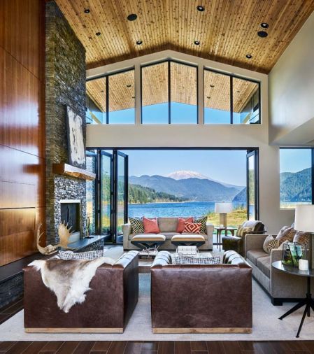 Panels of walnut hide the television; a reclaimed Juniper mantel adds panache to the rock fireplace from Lisac’s Fireplaces & Stoves. Kolbe Doors and black aluminum Marlan windows from Portland Millwork.