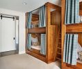 Curtains enable children to get better rest; LED lights make easy reading; plug-ins charge electronics. Bottom bunks feature storage. Laundry behind sliding barn door.