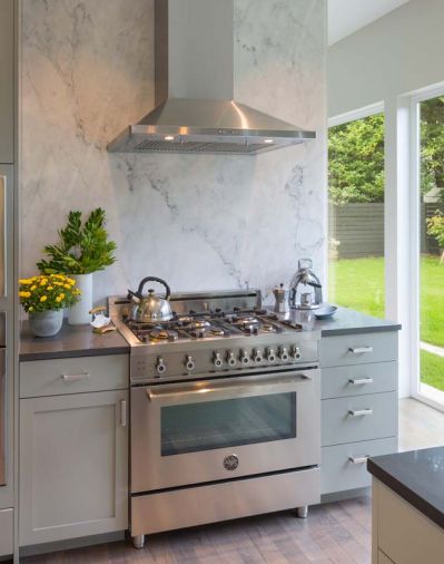 Adding a marble accent wall behind the oven and range brings texture and interest to the kitchen. Jill says this was one area where a little bit of extra spending produced an outsized impact in terms of design.