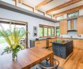 In the kitchen, a motorized control allows residents to open the clerestory window above the range for natural ventilation. White ceilings with exposed wood beams give it a crisp, farmhouse-inspired look. “We wanted the ceilings to be as light as possible so the interior would glow with natural light,” says architect Nathan Good.