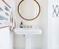 The powder room off the kitchen features simple, crisp lines. “I loved bringing the wood in with the mirror because it warms up all the white,” says Heidi. Geometric tile is from Cement Tile Shop.