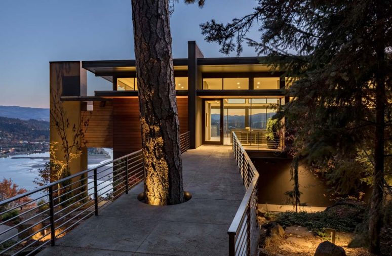 A simple-span bridge accommodates a towering fir, which mimics the monolithic column at left that houses the outdoor kitchen with deck.