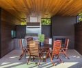 A pass through window connects the adjacent indoor kitchen with the covered outdoor one. Jensen Jarrah outdoor furniture warms the space.