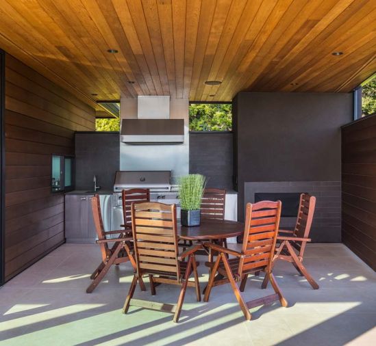 A pass through window connects the adjacent indoor kitchen with the covered outdoor one. Jensen Jarrah outdoor furniture warms the space.