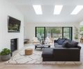 Generous Pella sliding glass doors and wood floors help pull the forested backyard and living room together. Sectional by Camerich, coffee table by Four Hands, and Jute Ottomans by Safavie add modern flair.