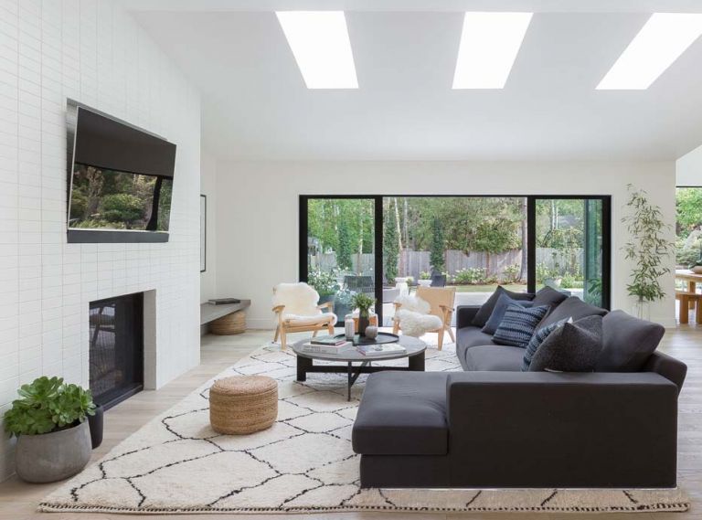 Generous Pella sliding glass doors and wood floors help pull the forested backyard and living room together. Sectional by Camerich, coffee table by Four Hands, and Jute Ottomans by Safavie add modern flair.
