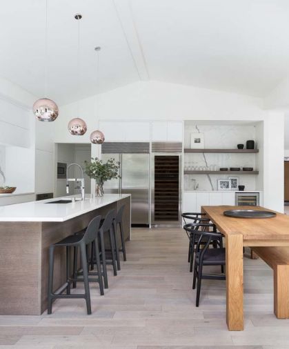 Durable cedar stone countertops in Arctic White from MS International, along with white cabinets from Belmont Cabinets help create a light, open, scandinavian feel. The brightness is married seamlessly with the wood floors from Kentwood, and the “Big Sur” kitchen table from Crate & Barrel. Copper pendants over the island from Tudo and Co. add a modern touch.