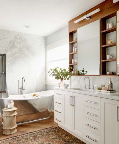 The bookmatched marble makes a stunning backdrop to the Waterworks tub. Robern medicine cabinets bordered by walnut perimeter,