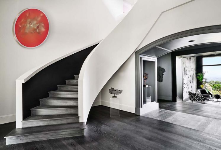 The original drywall staircase that had a wooden railing became all drywall; stair treads are engineered wood from Castle Bespoke Flooring; LED strip lighting lights black staircase wall. Peter Gronquist painting hovers like the moon.