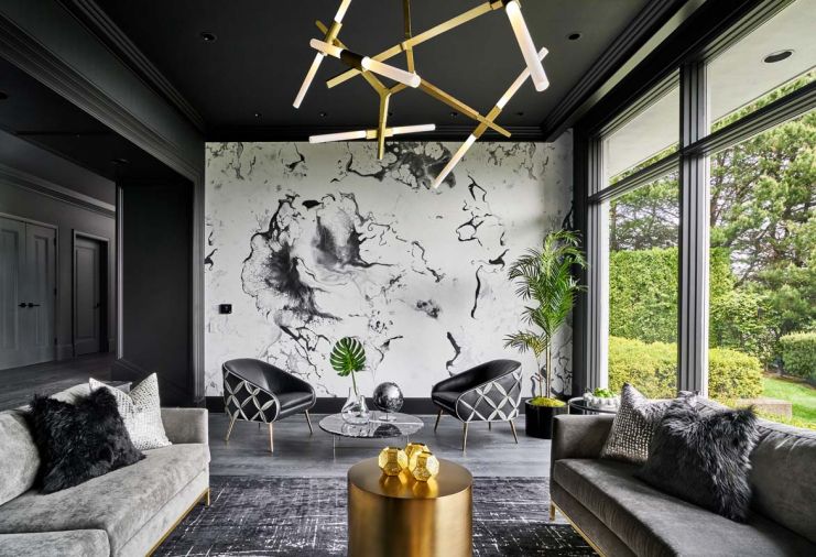 Touches of gold add bling to the dramatic black, gray and white color scheme found in the living room – from the graduated circular DWR coffee tables to the angular Agnes Chandelier. The outside comes in with a potted palm crowned in chartreuse moss, a mound of limes and a faux leaf sprouting from a glass vase.