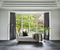 Black metallic draperies flank a neutral tête-à-tête sofa, DWR floor lamp and side table.