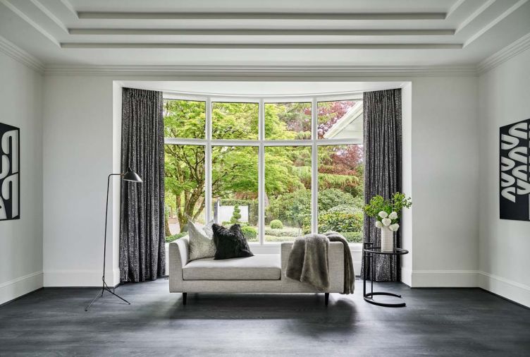 Black metallic draperies flank a neutral tête-à-tête sofa, DWR floor lamp and side table.