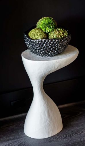 Interesting shapes and textured white side table pops against black wall.