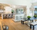 A reflective white lap siding ceiling brings light into kitchen. Phillip Jeffries grass cloth panels add panache to the bar. Curry & Co. French Empire crystal chandelier brings shine to Vanillawood sourced table; Kravet upholstered benches.