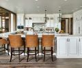 To create more intimacy in the kitchen, the ceiling was dropped to counter the expansive, high ceilings in the adjacent living room. A wraparound counter with room for six barstools gives plenty of space for not only eating, but also doing homework under an adult’s watchful eye. Kitchen cabinets by Hayes Cabinetry are glazed to soften the whiteness. A large island invites family and friends to gather and chat.