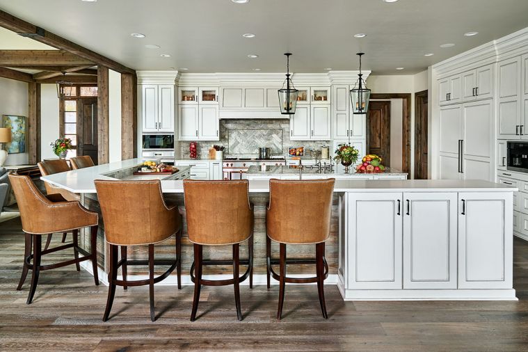 To create more intimacy in the kitchen, the ceiling was dropped to counter the expansive, high ceilings in the adjacent living room. A wraparound counter with room for six barstools gives plenty of space for not only eating, but also doing homework under an adult’s watchful eye. Kitchen cabinets by Hayes Cabinetry are glazed to soften the whiteness. A large island invites family and friends to gather and chat.
