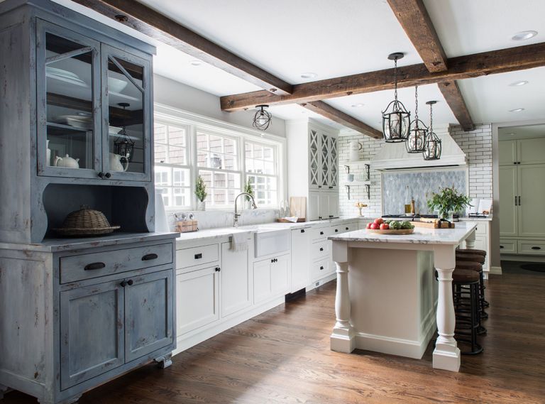 To underscore the home&rsquo;s established farmhouse style, Taryn designed a rustic hutch to bring a warmer, more traditional feel into the kitchen. Countertops and backsplash are Calacatta Vettogli marble sourced from Intrepid Marble & Granite. &ldquo;Throwing in a lot of texture was important,&rdquo; says Taryn. &ldquo;In the kitchen alone, you have this really cool Ann Sacks white brick behind the range, the distressed wood hood, the hutch, and the backsplash, which is a beautiful glass mosaic.&rdquo;