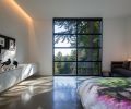 The master bedroom suite features softer cove lighting for a restful feel. Art, including the bedspread, is displayed prominently.