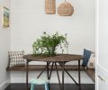 A built-in breakfast nook serves double-duty as an afternoon homework station. Cushion-free benches are easy to clean and maintain. Tight shiplap on the wall at the back of the nook gives the area a rustic feel, underscored by a vintage stool.