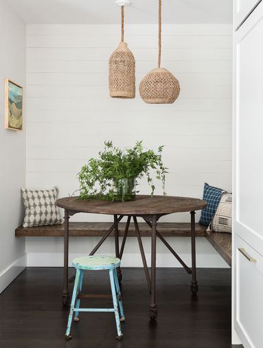 A built-in breakfast nook serves double-duty as an afternoon homework station. Cushion-free benches are easy to clean and maintain. Tight shiplap on the wall at the back of the nook gives the area a rustic feel, underscored by a vintage stool.