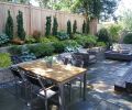 Shade-friendly foliage plants including hosta, Japanese maple, Japanese forest grass, heuchera, and Irish yew spill from terraced beds constructed from cost-effective, attractive concrete blocks. “The vertical forms of the Irish yew help break up that long fence line,” explains Tim.