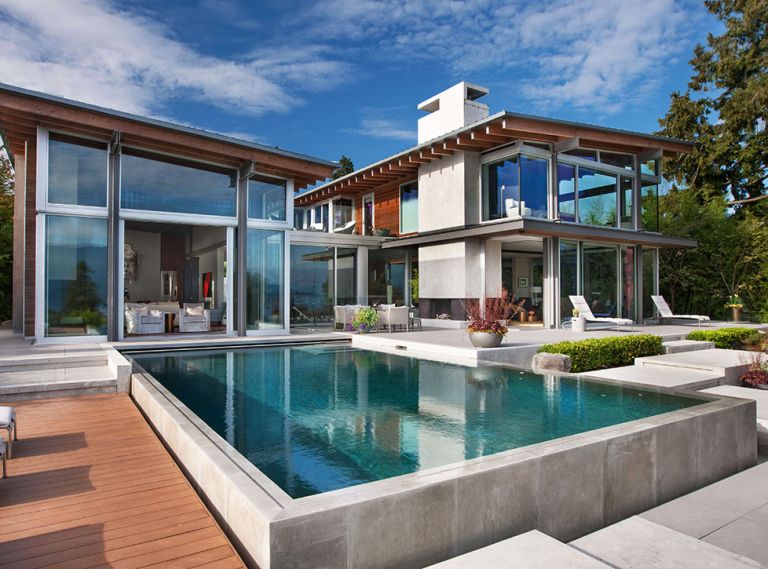 Exposed beams inside and out team with concrete chimney and fireplaces. Poured concrete exterior forms for the stairs, pool and koi pond by GCW.
