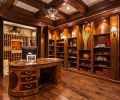 Cherry wainscot paneled built-in, walnut/burl partners desk lead to glass wine cellar doors.