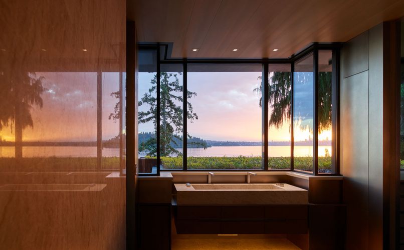 Double Taj Mahal stone master sink looks out over planted flat green roof toward views. Polished Brazilian quartzite wall mirrors view.