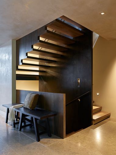 Staircase with bench and pony wall descends from the living/dining level to lower level and rises to the first landing, childrens’ bedrooms and bath.