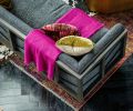 A hot pink throw pops against custom fabric on an Arteriors sofa.