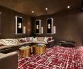 A Cloud sectional in performance linen by Restoration Hardware Modern adds comfort to the theater experience. Luxurious gray and oxblood jewel tone custom wall-to-wall Davis & Davis carpet adds plushness underfoot. Thayer Coggin Design Classic golden drum tables add sparkle.