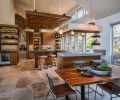 A mix of materials, colors, and textures gives this kitchen a dynamic feel and echoes the rich natural world of the Oregon Coast. Quartz countertops are used in two different thicknesses and colors. The large-format porcelain floor tiles have a warm, stone-like finish. Custom walnut cabinetry is grain-matched for extra interest.