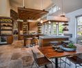 A mix of materials, colors, and textures gives this kitchen a dynamic feel and echoes the rich natural world of the Oregon Coast. Quartz countertops are used in two different thicknesses and colors. The large-format porcelain floor tiles have a warm, stone-like finish. Custom walnut cabinetry is grain-matched for extra interest.