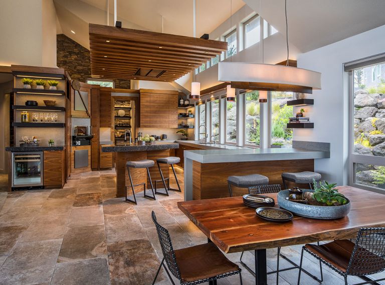 A mix of materials, colors, and textures gives this kitchen a dynamic feel and echoes the rich natural world of the Oregon Coast. Quartz countertops are used in two different thicknesses and colors. The large-format porcelain floor tiles have a warm, stone-like finish. Custom walnut cabinetry is grain-matched for extra interest.