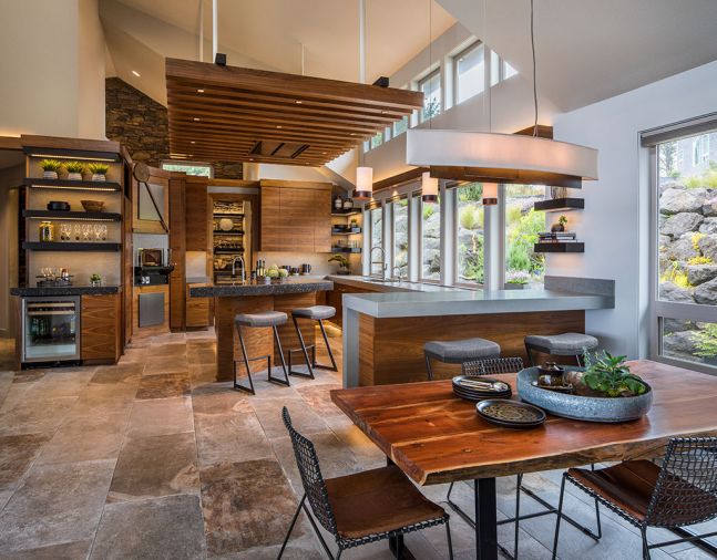 A mix of materials, colors, and textures gives this kitchen a dynamic feel and echoes the rich natural world of the Oregon Coast. Quartz countertops are used in two different thicknesses and colors. The large-format porcelain floor tiles have a warm, stone-like finish. Custom walnut cabinetry is grain-matched for extra interest.