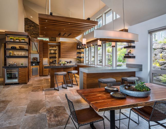 A mix of materials, colors, and textures gives this kitchen a dynamic feel and echoes the rich natural world of the Oregon Coast. Quartz countertops are used in two different thicknesses and colors. The large-format porcelain floor tiles have a warm, stone-like finish. Custom walnut cabinetry is grain-matched for extra interest.