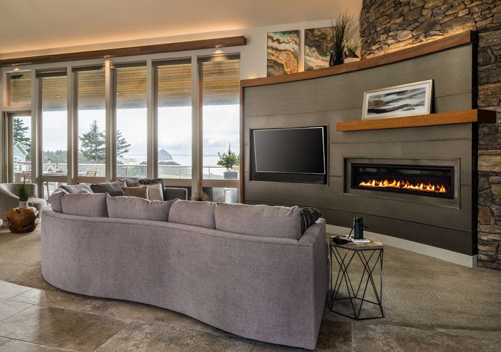 The focal point of the living room is a custom-built half-height metal wall that houses the fireplace and television. To complement the cylindrical shape of the adjacent two-story turret, the wall is also curved, but in the opposite direction. Instead of mounting the television over the fireplace, the side-by-side placement created better ergonomics for viewing.